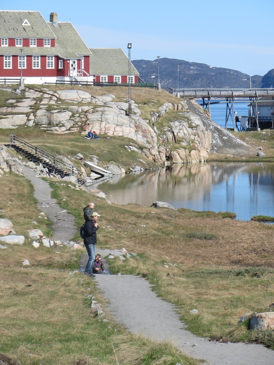 På en klippe i Grønland ligger en rød træbygning, Aasiaat Folkebibliotek